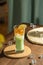 Refresh drinks, summer beverage, a matcha green tea latte with honey jelly and sliced lemon in a tall glass on a round cork