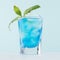 Refreshing alcohol drink blue Hawaii in misted rich shot glass with ice cubes, green mint in modern pastel mint beach bar interior