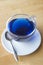 Refreshing blue chinese tea in a transparent mug on a wooden table