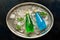 Refreshing bottled drinks, green tarragon lemonade and blue drink on a metal tray with ice cubes and mint leaves. Top view, flat