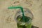 Refreshing cocktail with straw, mint and lemon on a sandy beach. summer vacation. delicious drink. background for the design.
