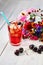 Refreshing drink with cherries and apples on a white wooden table. Summer cold lemonade