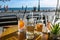 Refreshing drinks in drinking glasses and bottles on a table in a seaside street cafe, blurry people walking on the promenade at