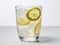 Refreshing glass of lemonade with ice cubes and lemon slices on white background