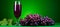 Refreshing grape juice in glass on wooden table with green background for text placement