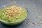 Refreshing green smoothie in glass bowl with green buckwheat sprouts on grey background. Raw dish. Close up shot. Helthy vegetable