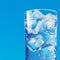 Refreshing ice water Glass with ice cubes on blue background