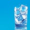 Refreshing ice water Glass with ice cubes on blue background
