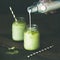Refreshing iced coconut matcha latte in glass jars, copy space