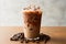 Refreshing iced coffee in a plastic cup with scattered coffee beans on a clean white background