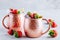 Refreshing iced Moscow mule alcoholic cocktail in copper mugs with strawberry and lemon