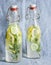 Refreshing lemonade with rosemary, cucumber and lemon in bottles. Summer cool drink on a blue background