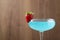 Refreshing light blue cocktail with strawberry on blurred background, space for text