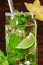 Refreshing mojito beverage with rum, fresh lime, mint, crushed ice and decorative carambola on a dark wooden background.