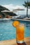 Refreshing orange cocktail with a slice garnish by a serene poolside on a sunny day