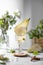 Refreshing Pear cocktail lemonade in a glasse with pear puree and fresh fruit and flowers on light gray table background