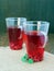 Refreshing pomegranate tea, drink with mint in two tall glass mugs