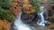 Refreshing scene of beautiful waterfall among colorful autumn trees on mountain for background