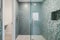 refreshing shower in stylish bathroom with lofi wallpaper, glass tile and sleek fixtures