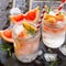 Refreshing summer drink with ice with rosemary and grapefruit on a stone background.