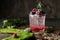 Refreshing summer drink with syrup, raspberry, blackberry and ice on dark background