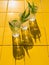 Refreshing summer drinks in crystal glasses with green leaves yellow tile background harsh shadows cold natural cocktail