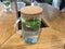 Refreshing water with lemon lime and mint sprigs in a glass glass with a handle, closed with a cork lid on a light wood table