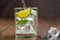 Refreshing water is poured into a glass with ice cubes, lime wedge and mint leaves.