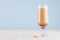 Refreshment coffee drink with cream, foam and cookies in wineglass in light blue interior on white wooden table, copy space.