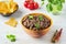 Refried beans, a dish of black beans, fried onions and spices in a yellow ceramic bowl on a light wooden background. Bean dishes.