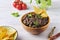 Refried beans, a dish of black beans, fried onions and spices in a yellow ceramic bowl on a light wooden background. Bean dishes.