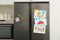 Refrigerator with child`s drawings, note and magnets in kitchen