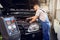 Refueling the air conditioner. A mechanic pumps freon into the air conditioning system at a car service