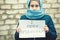 Refugee girl with an inscription on a white sheet