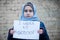 Refugee girl with an inscription on a white sheet