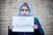 Refugee girl with an inscription on a white sheet