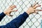 Refugee hands on the fence of barbed wire