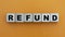 REFUND - word on wooden cubes on a beautiful yellow background