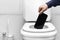 refusal of the phone. a man& x27;s hand throws the phone into the toilet because of a breakdown or refusal of calls and