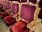 regal ornate rounded wood armed formal empty red velvet opera or movie or theatre chairs in curved row