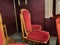 regal ornate rounded wood armed formal empty red velvet opera or movie or theatre chairs in curved row