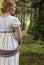 Regency woman in cream dress walks alone in a summer garden