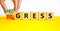 Regress or progress symbol. Businessman turns wooden cubes and changes the word Regress to Progress. Beautiful yellow table white