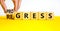 Regress or progress symbol. Businessman turns wooden cubes and changes the word Regress to Progress. Beautiful yellow table white