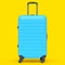 Regular blue polycarbonate suitcase isolated on yellow background.