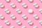 Regular pattern of open jars of cream on a pastel pink background. Minimal skin care concept