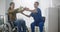 Rehabilitation doctor helping patient in wheelchair to workout with stretch band