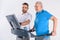 rehabilitation therapist assisting senior man exercising on treadmill