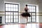 Rehearsal ballerina in the hall. Wooden floor, very large windows. Beautiful ballerina in the rehearsal room