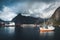 Reine, September 2018: Ship with rainbow in the background in the harbour of famous tourist attraction of Reine in